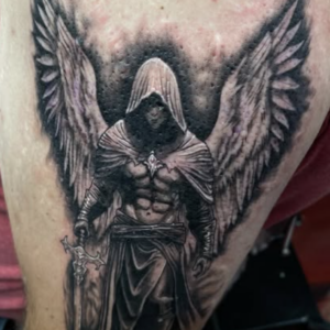 Hooded dark angel with large wings and a sword tattoo on the thigh, in black and gray shading